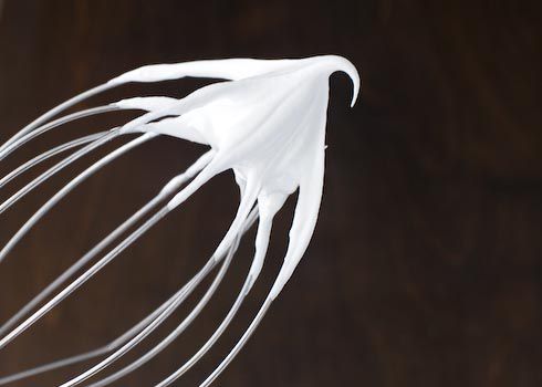 A whisk attachment holding meringue at firm peak. 