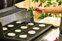 A person cooks onions in the Weber Genesis E-325 Liquid Propane Gas Grill