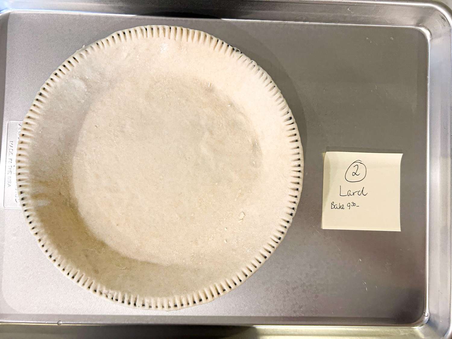 Prepared pie crust in a pan next to a note labeled Lard on a metal tray