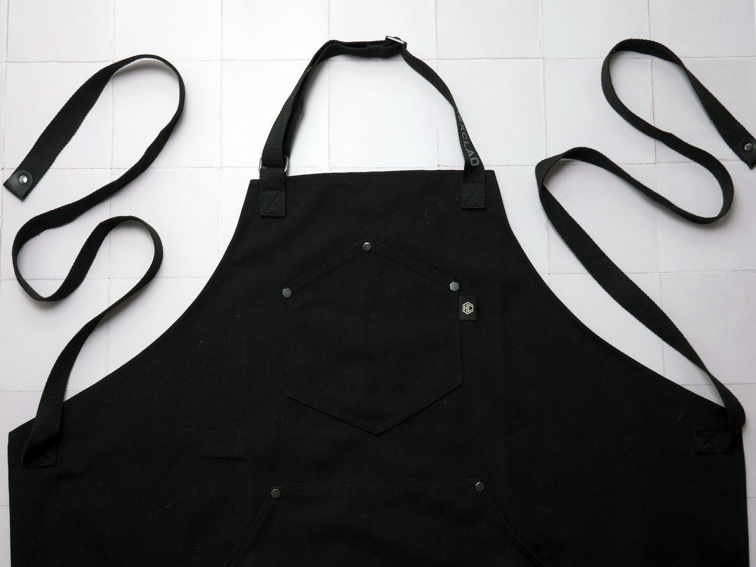 Hexclad apron on a white tile surface