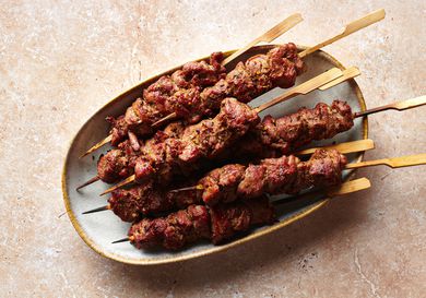 Skewers of spicy cumin lamb (yang rou chuan) on an oval platter.