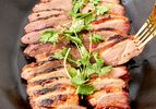 Sliced smoked duck breasts garnished with fresh herbs