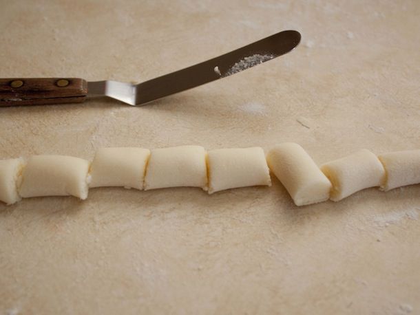 The rolled out dough is cut into bite-sized pieces with an offset spatula.