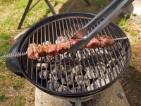 tongs grabbing a kabob on a charcoal grill