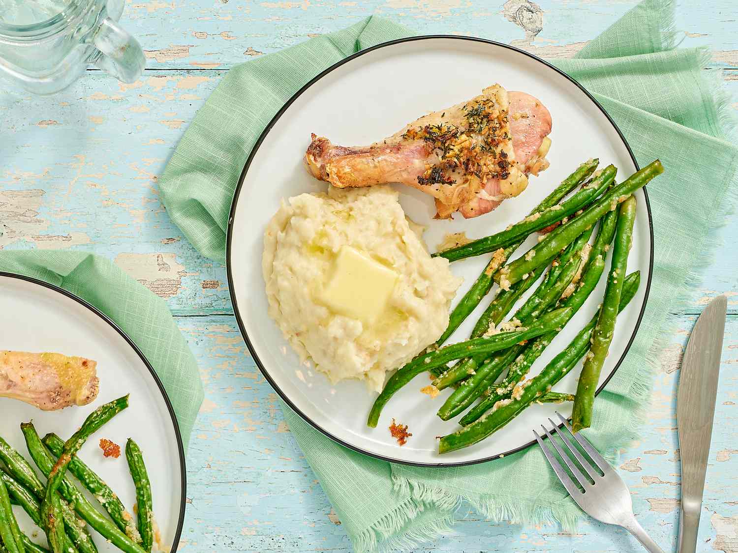 A plate with herbed chicken drumsticks mashed potatoes and green beans