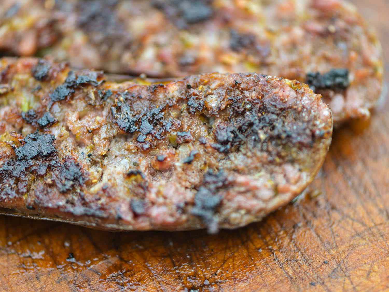 A loukaniko sausage has been split lengthwise and returned to the grill to brown on the cut sides.