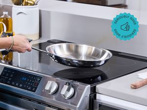 a person lifting the all-clad skillet from an electric stovetop