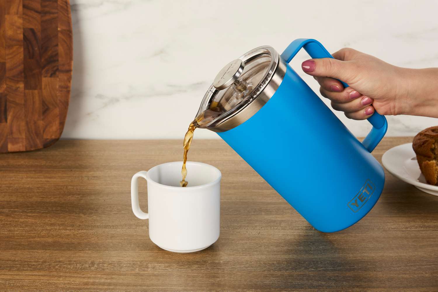 A person pouring coffee from the Yeti French press into a mug.