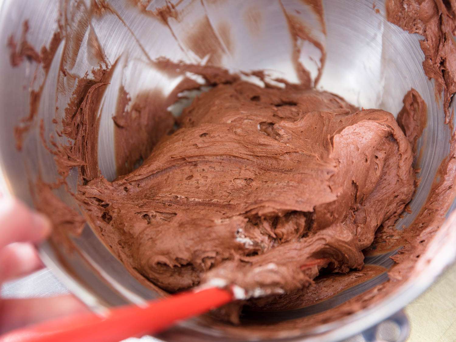 Gently folding whipped cream into eggless chocolate mousse.