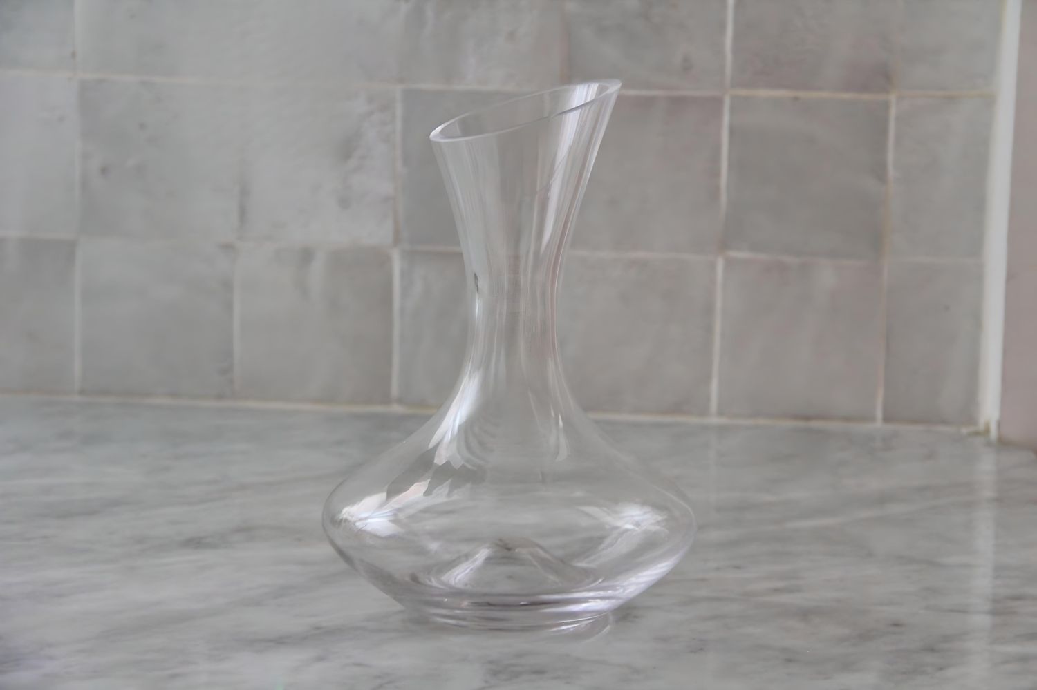 A closeup of the empty Godinger glass wine decanter on a marble surface