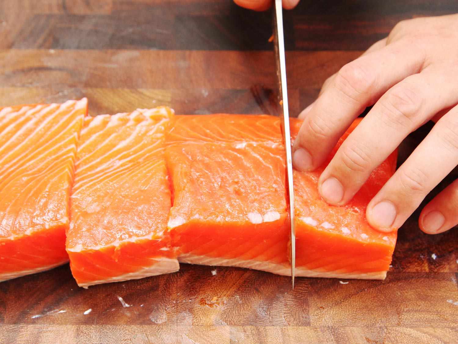 Close up photo showing portioning salmon fillet into five- to six-ounce portions