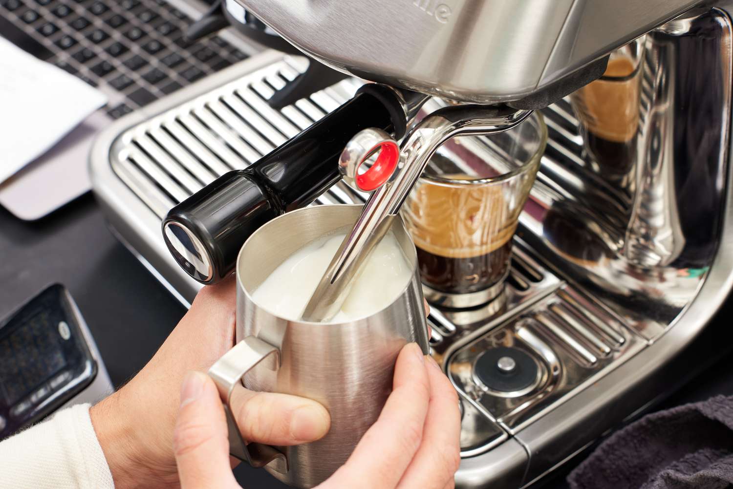 A person using the milk frother of the Breville Barista Touch Impress Espresso Machine with Grinder