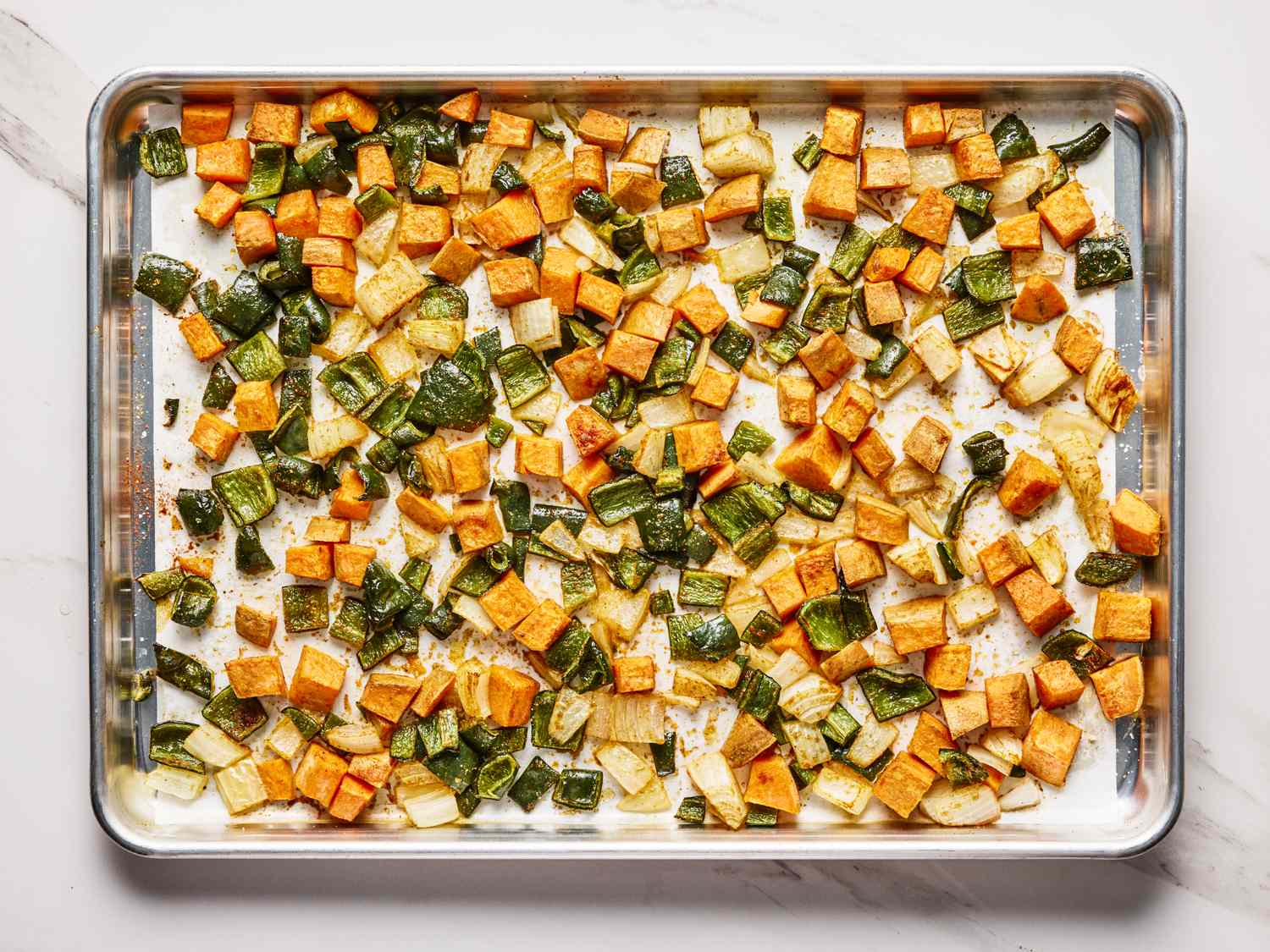 Diced sweet potatoes zucchini and peppers roasted on a baking sheet
