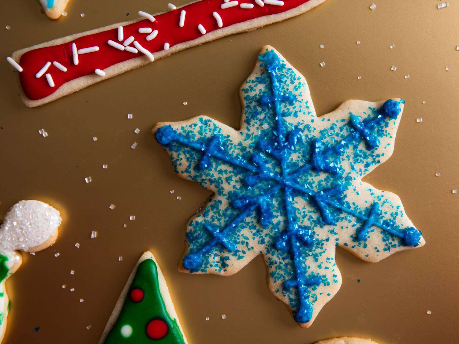 A snow flake-shaped cookie decorated with the flocking technique and blue sugar.