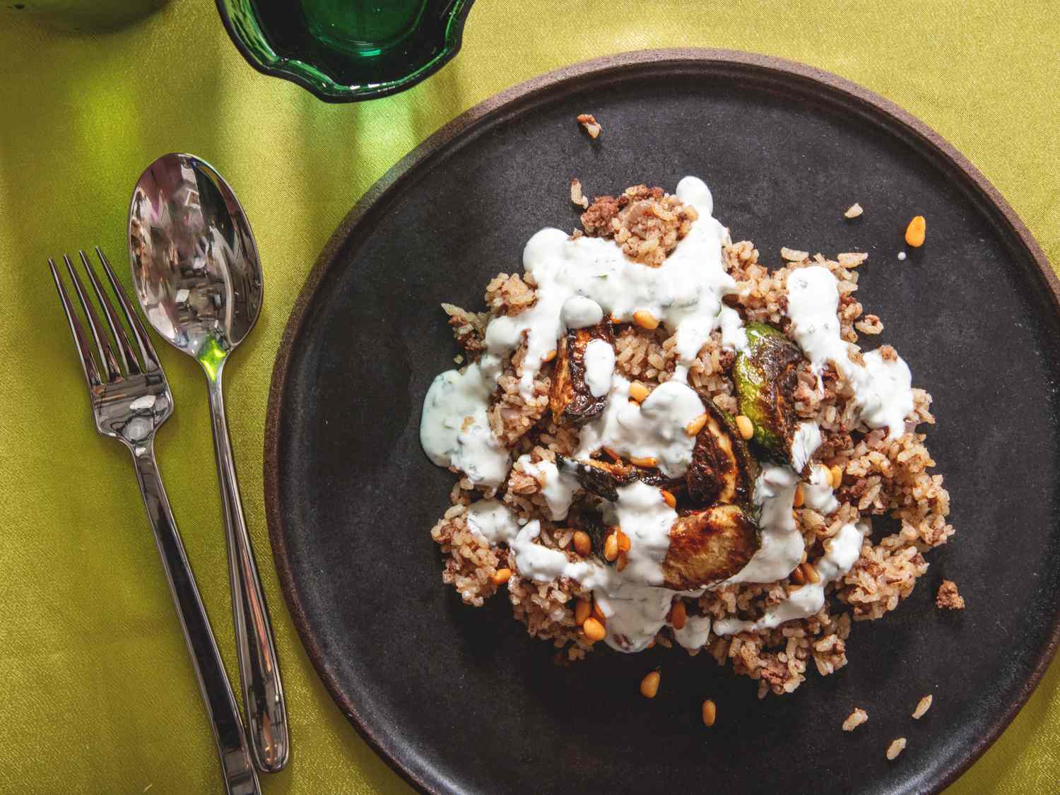 A dish with grain roasted vegetables and sauce on a black plate