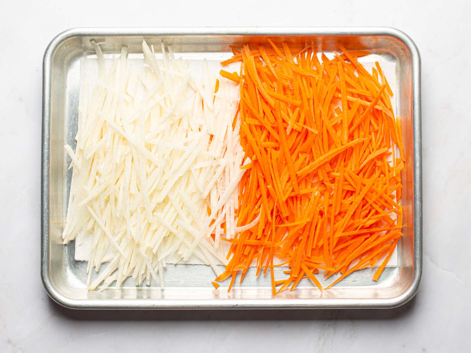 Overhead view of jiamca and carrots on a sheet tray 