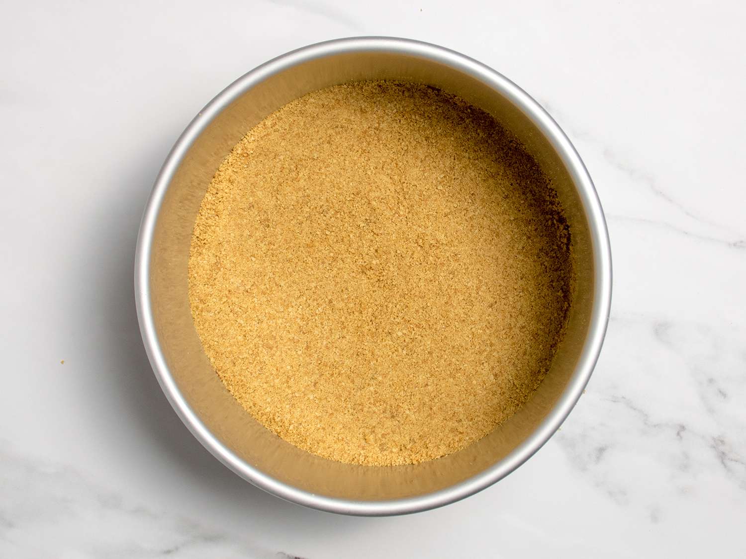 The cookie crumb crust packed into the cheesecake pan in a smooth, even layer.