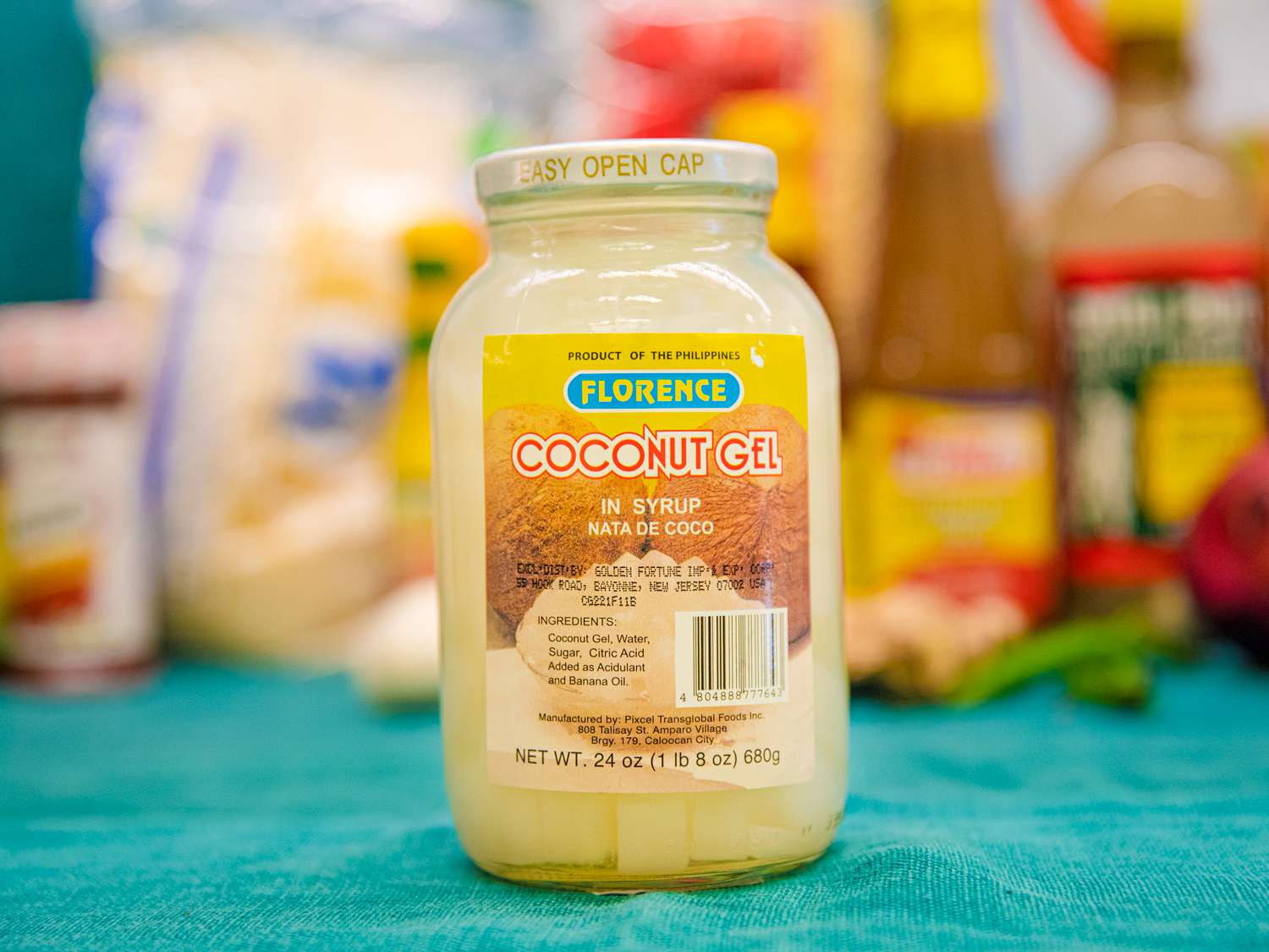 A jar of Coconut gel in syrup (Nata De Coco) on a blue background