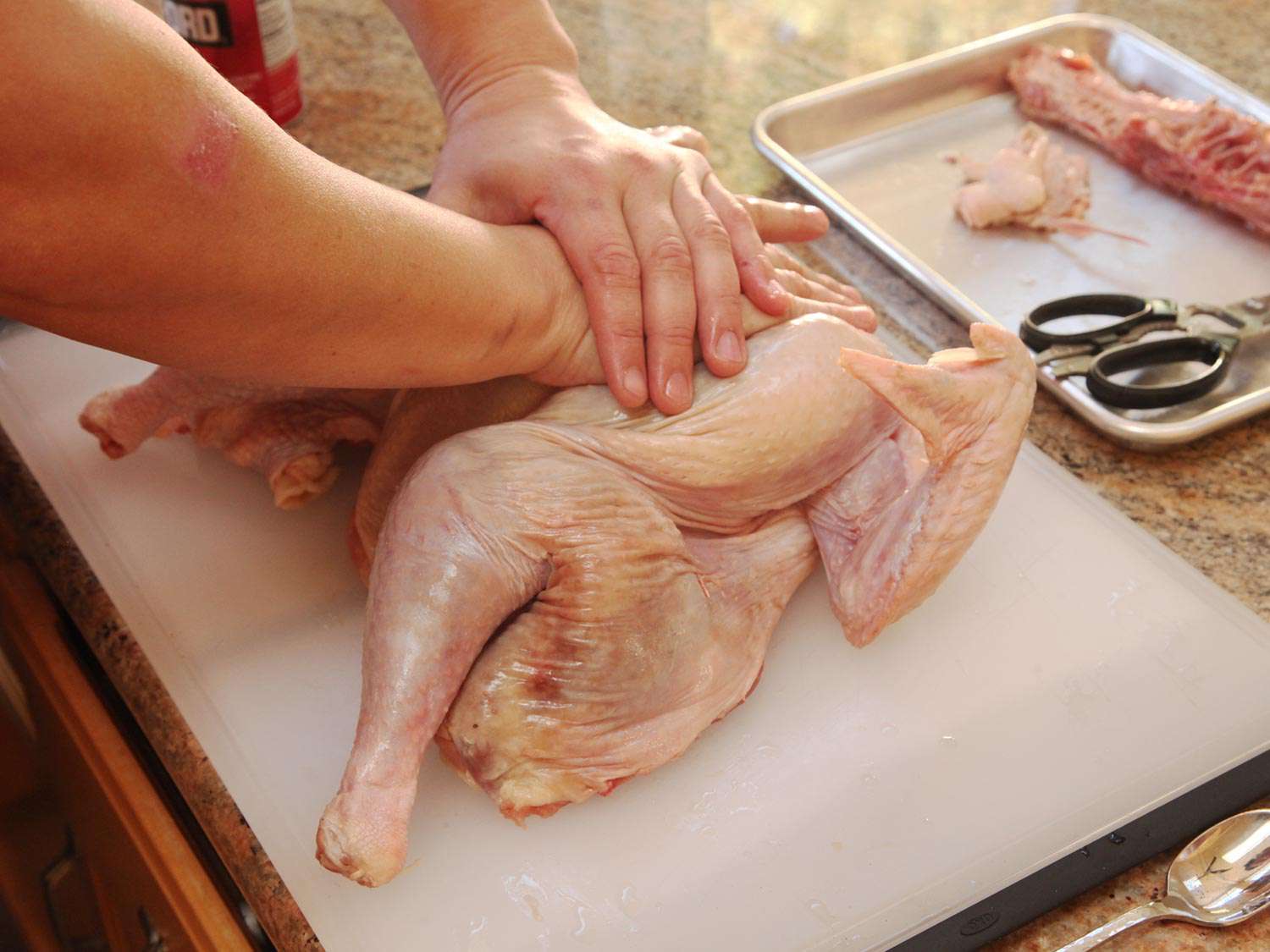 Author flattening the butterflied turkey by pressing down on its breast.