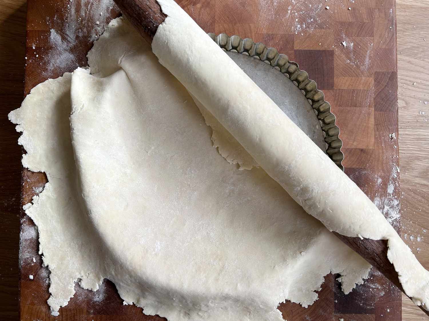 Pie dough being rolled onto a tart pan