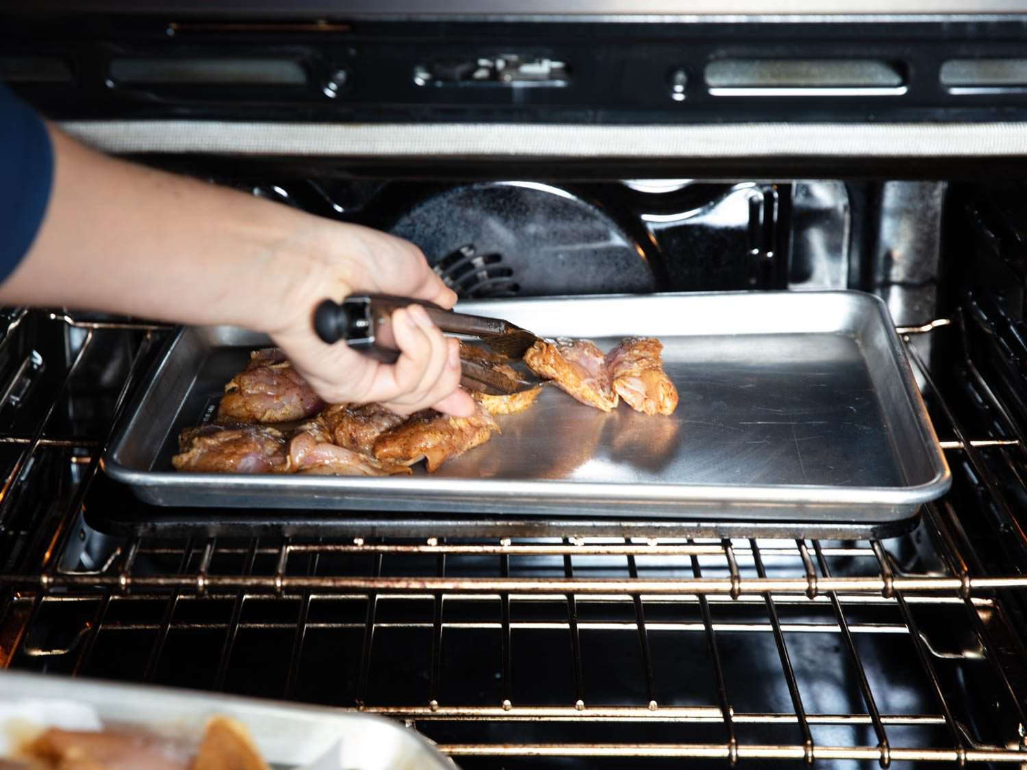 Putting marinated chicken on baking sheet under broiler