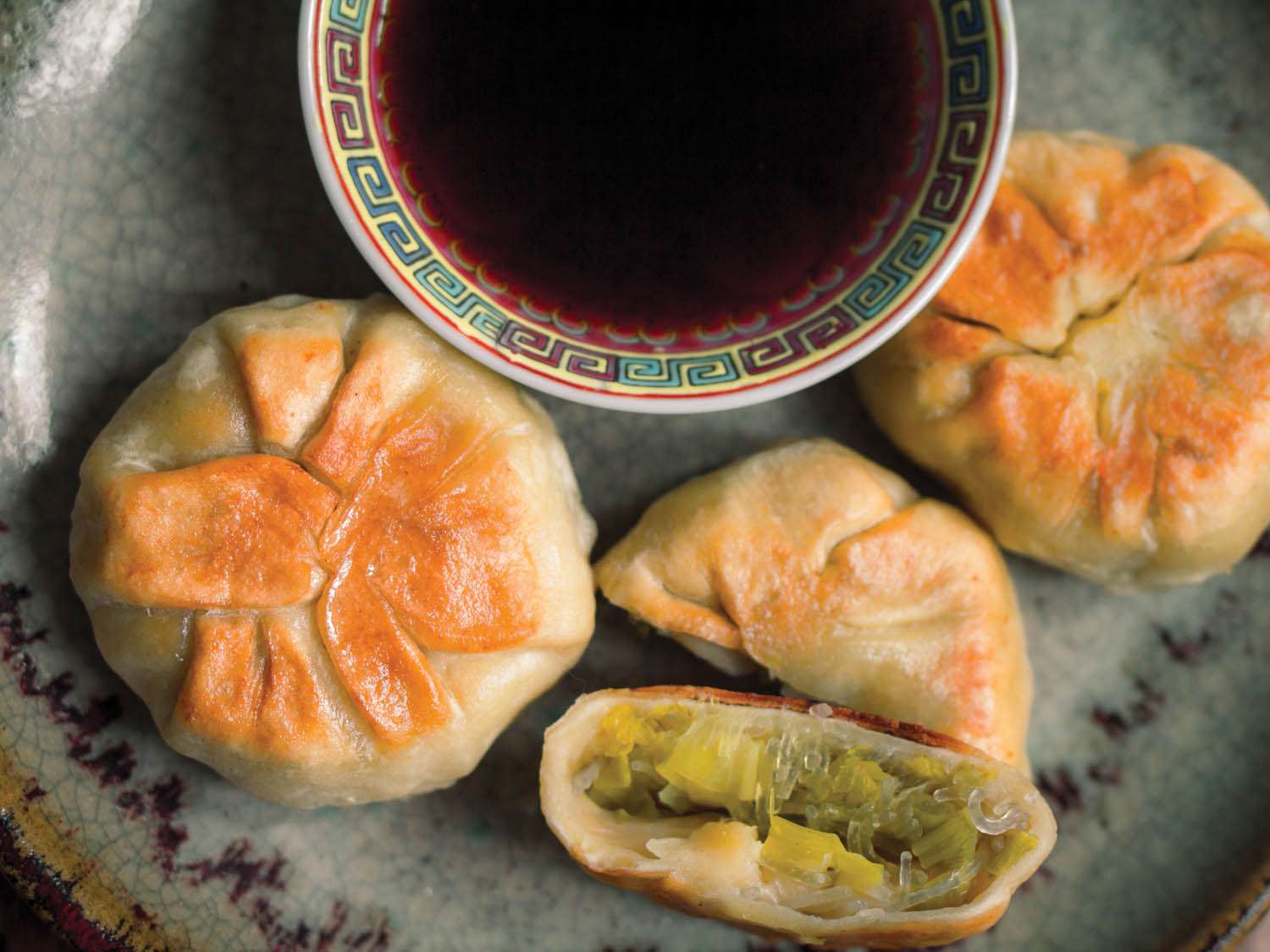 Golden pan-fried leek buns served with a bowl of soy dipping sauce