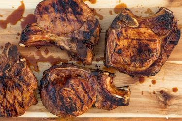 Overhead view of adobo-marinated grilled pork chops, resting on a cutting board.