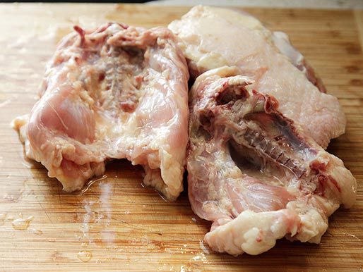 Raw chicken backs on wooden board