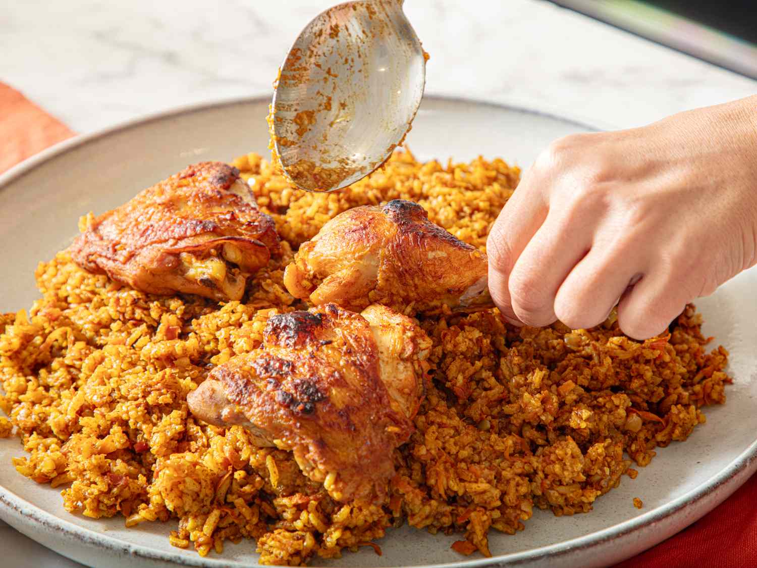 Chicken over rice being garnished with a spoon