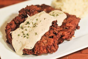 Pepper gravy spooned on chicken fried steak, served with mashed potatoes.