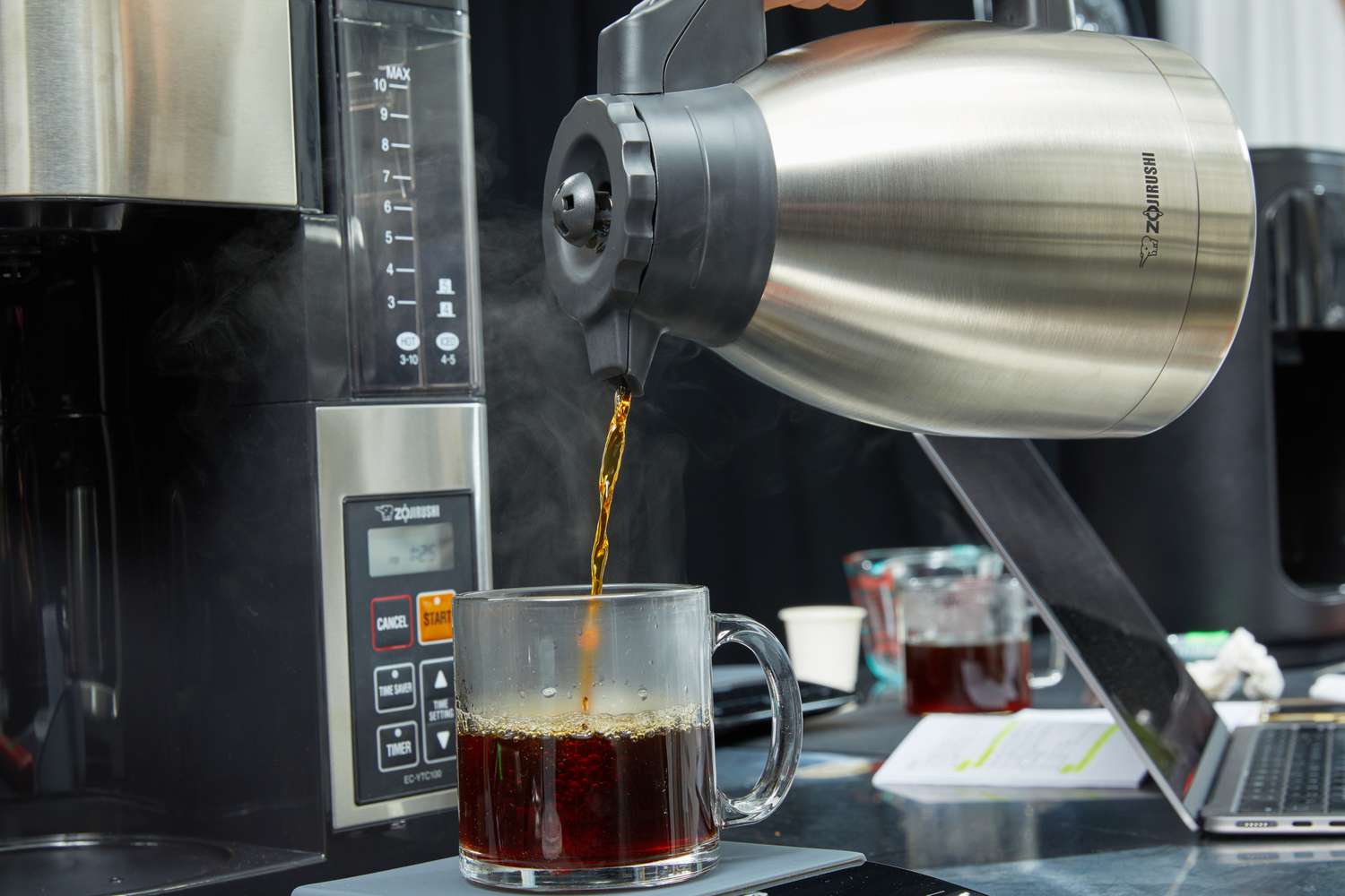 a person pouring from a thermal carafe into a coffee mug