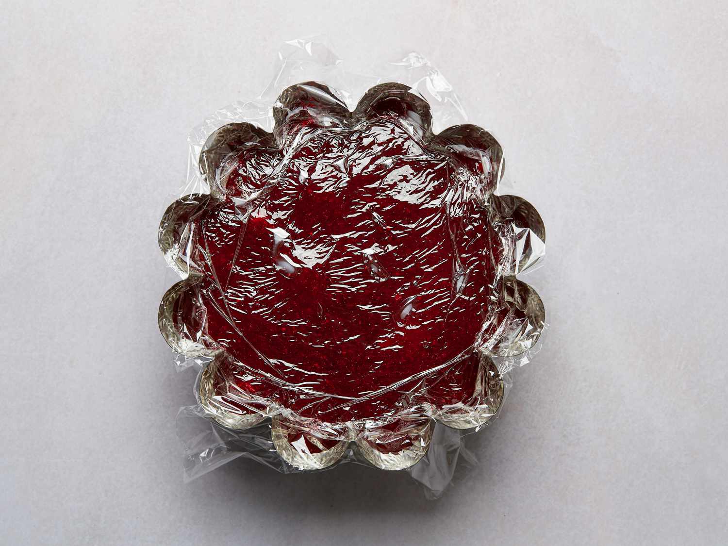 Cranberry sauce in a metal mold covered with plastic wrap 