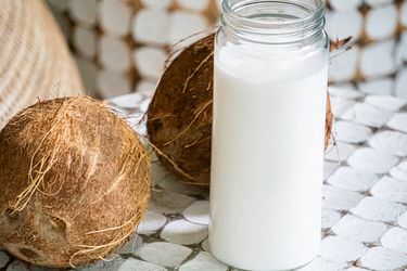 Side view of coconut milk surrounded by coconuts