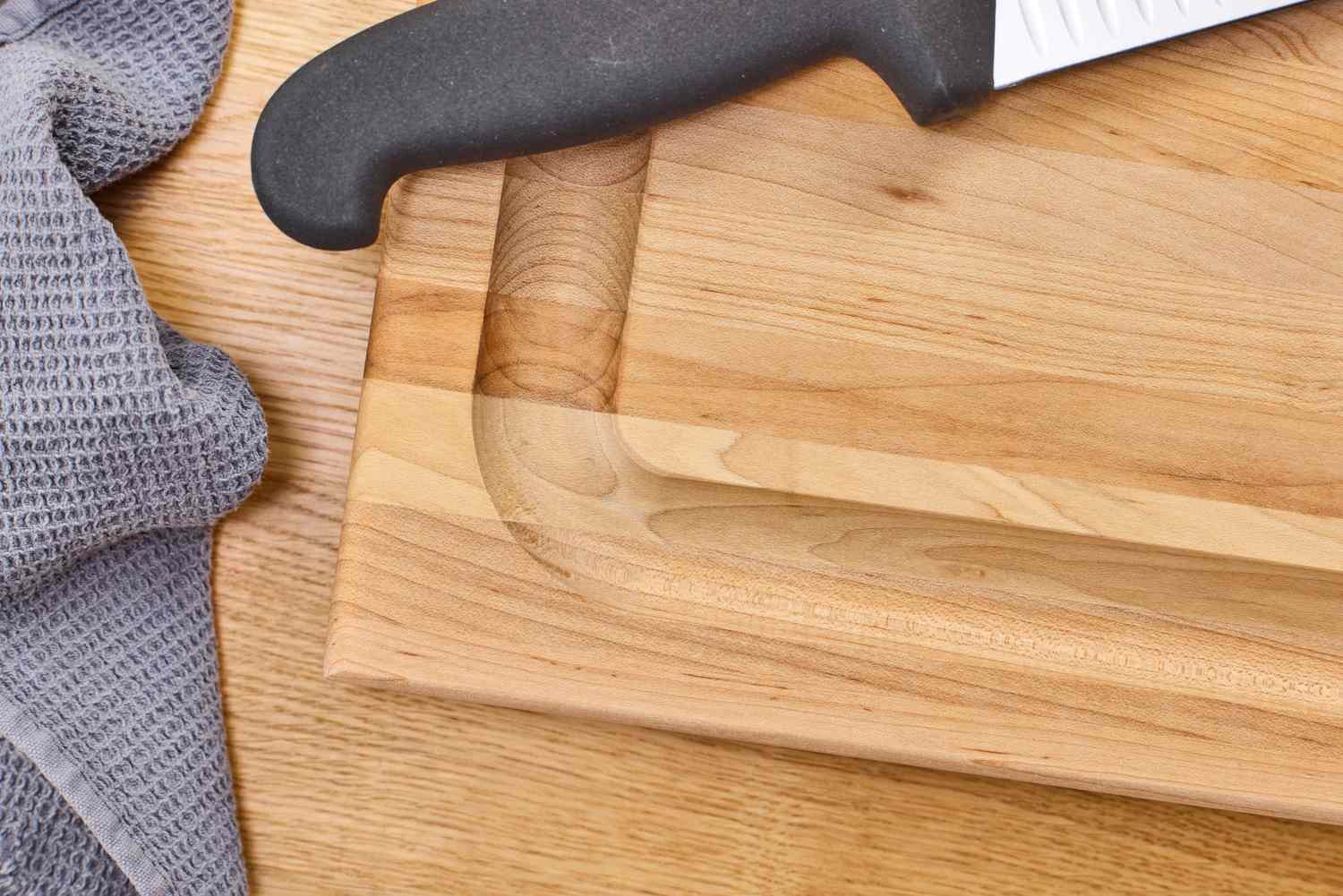 John Boos Reversible Maple Wood Cutting Board with Juice Groove with a knife handle and a textured cloth nearby