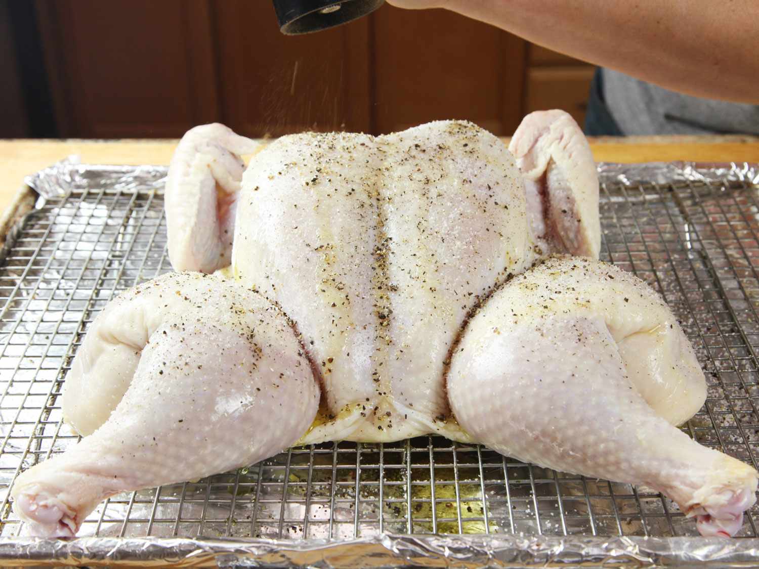 spatchcocked chicken on rimmed baking sheet with rack