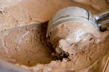 Closeup of mocha cashew ice creambeing scooped from a storage container.