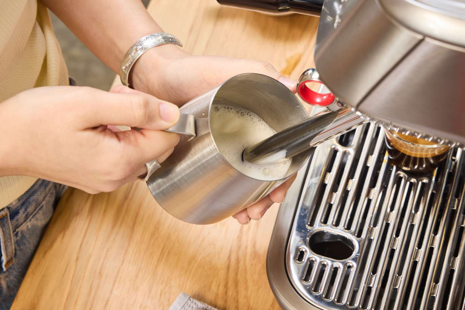 A person froths milk using the Breville The Oracle Jet Espresso Machine