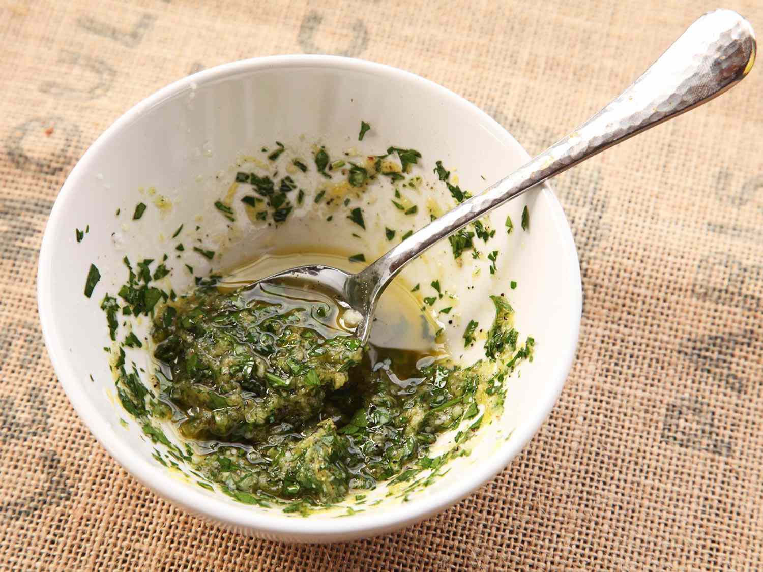 Stirring together gremolata ingredients with olive oil: parsley, garlic, and lemon zest.