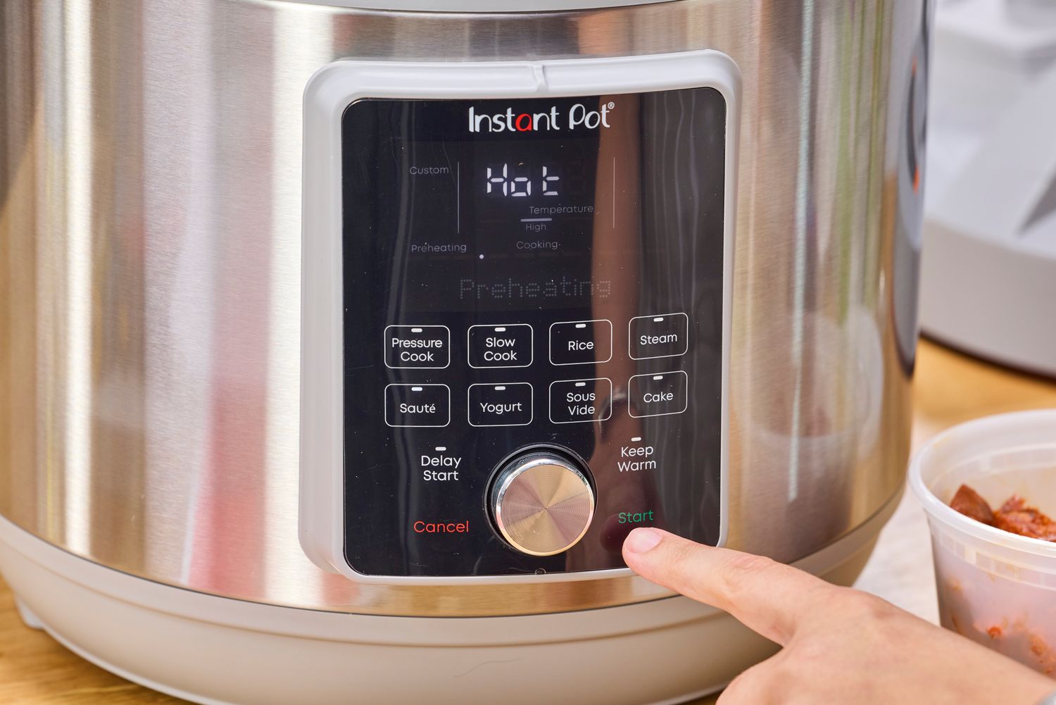 A person pressing the Start button on the Instant Pot Duo Plus 8-Quart Multi-Use Pressure Cooker V4