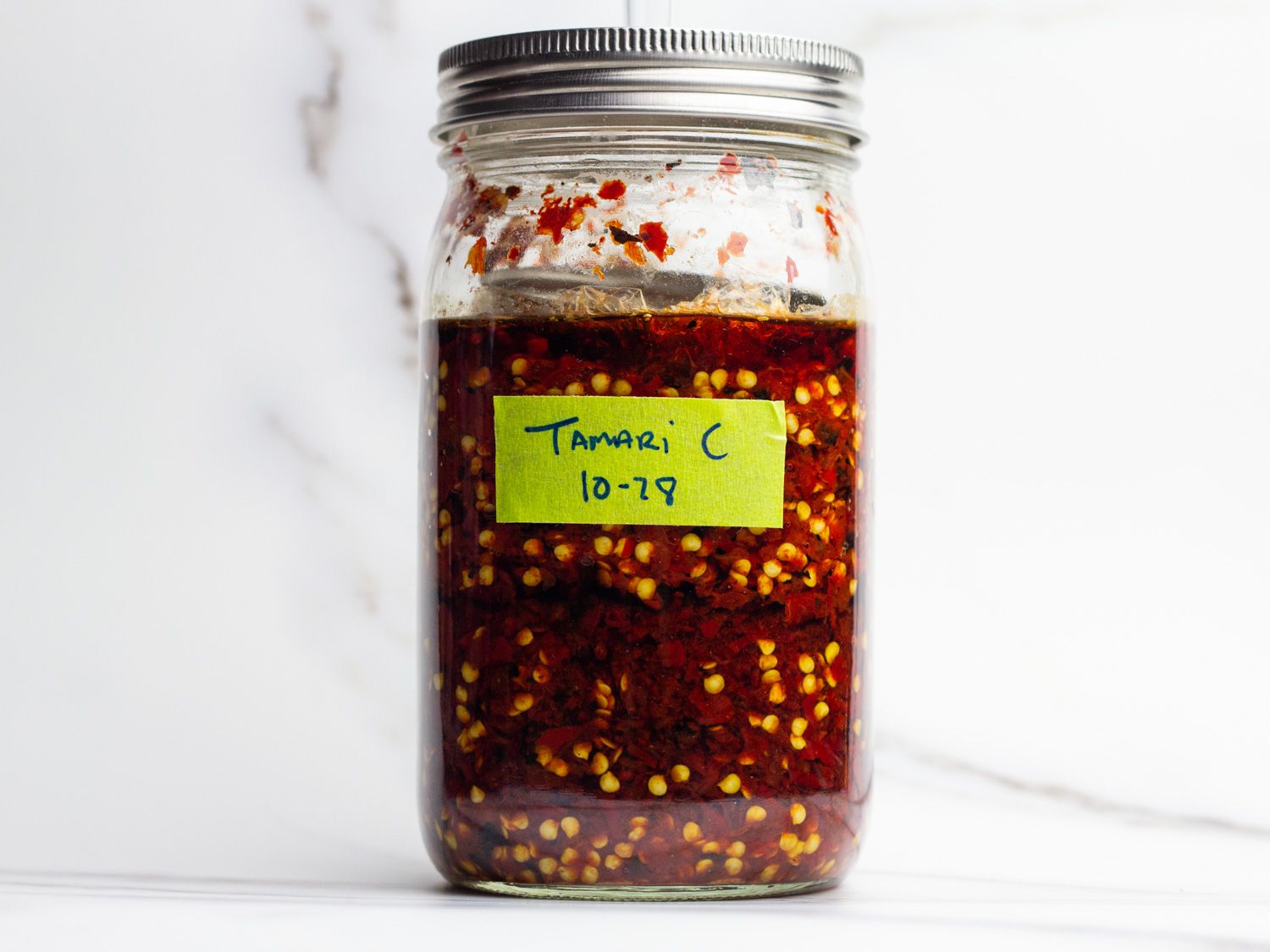 A jar of roasted and mashed chiles fermenting with an airlock in the lid.