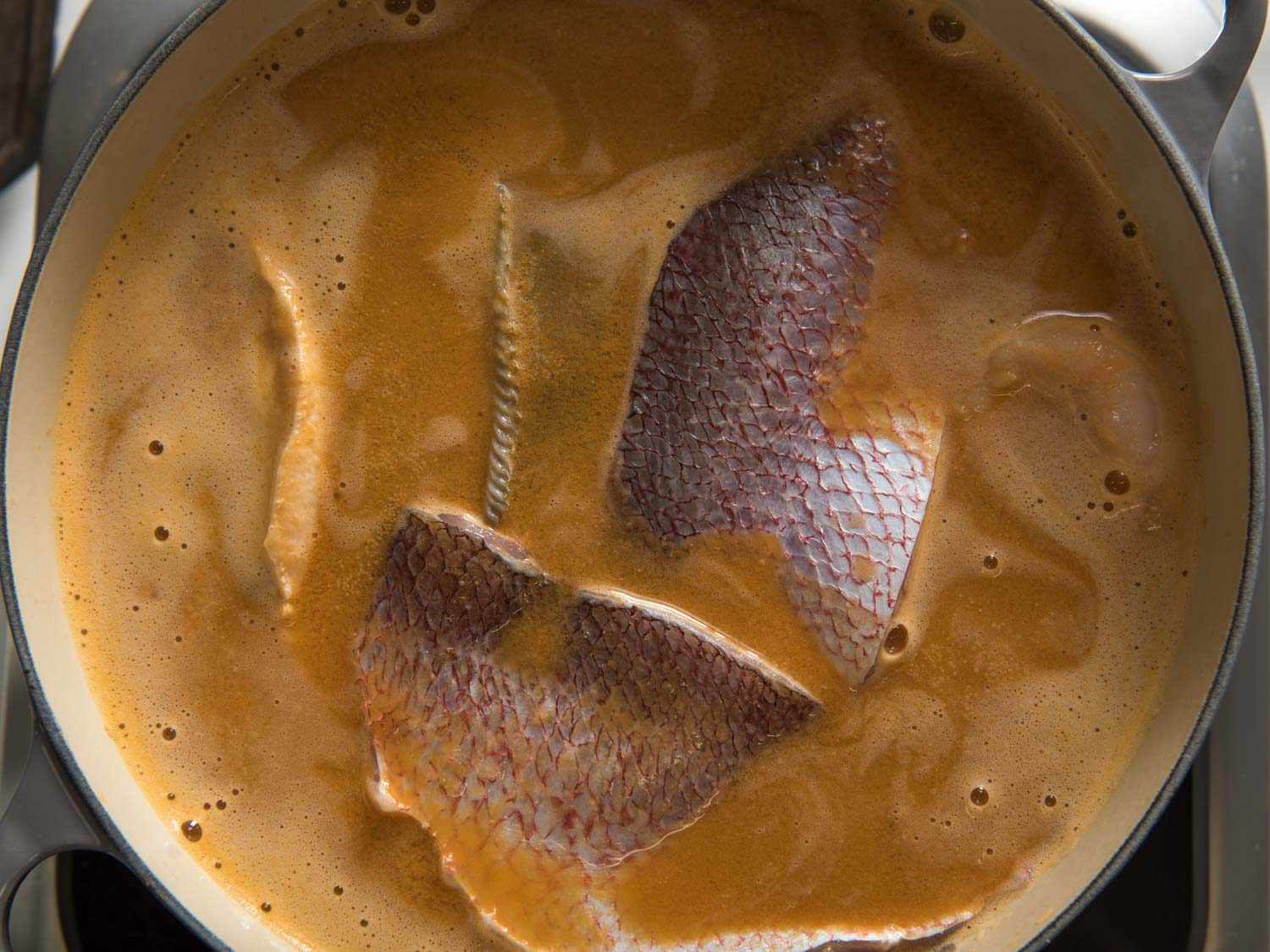 Poaching fish in the bouillabaisse broth.