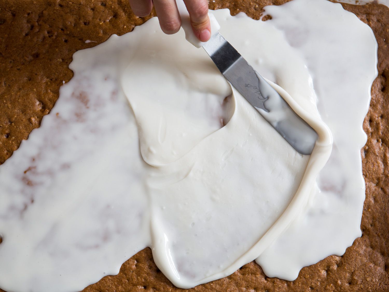 Spreading white glaze over Lebkuchen with an offset spatula