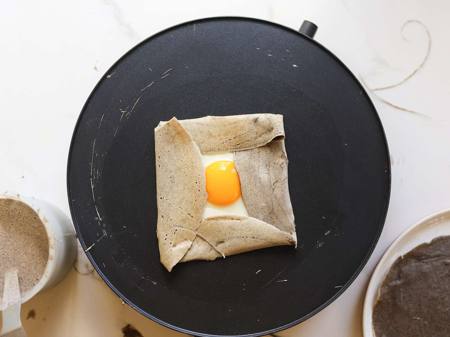 a folded buckwheat crepe with an egg on the electric crepe pan
