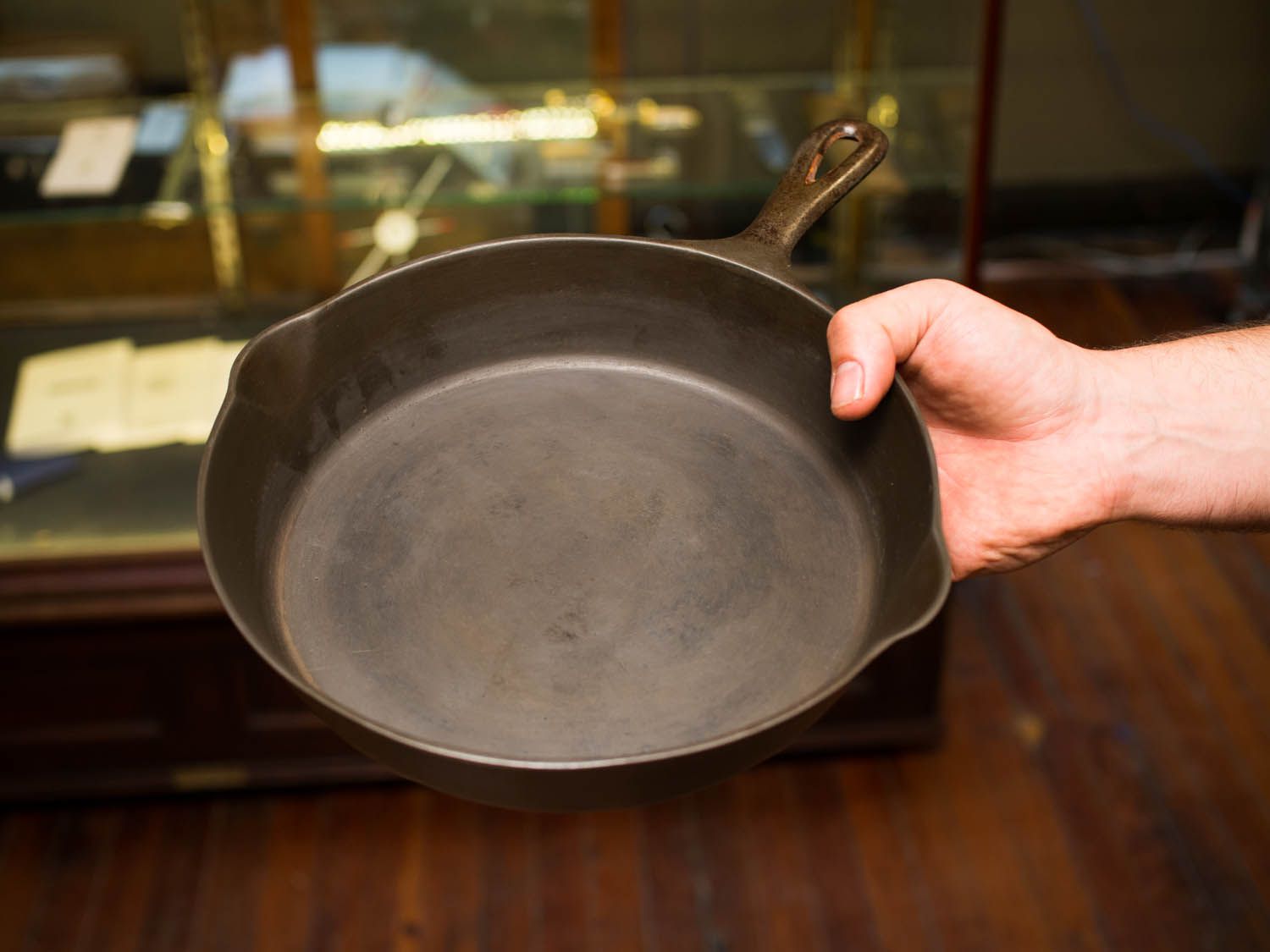 A hand holding a freshly cleaned and restored cast iron skillet.