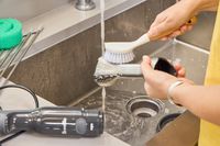 A person cleans the Breville Control Grip Immersion Blender with a small scrub brush