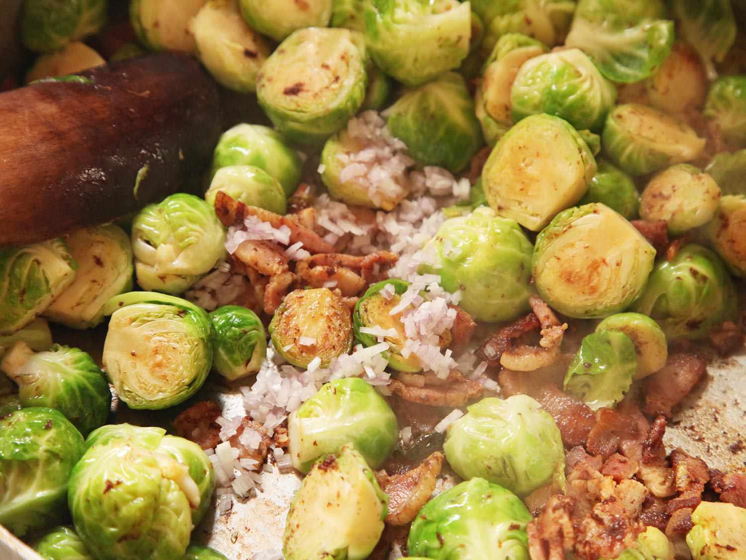Stirring minced shallots into Brussels sprouts and bacon