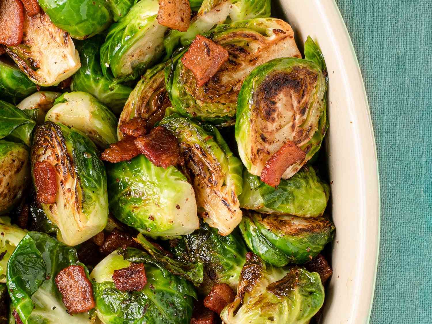 Roasted Brussels sprouts and bacon inside of a ceramic dish.