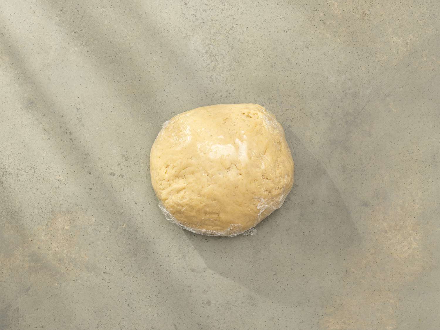 Overhead view of dough wrapped in plastic