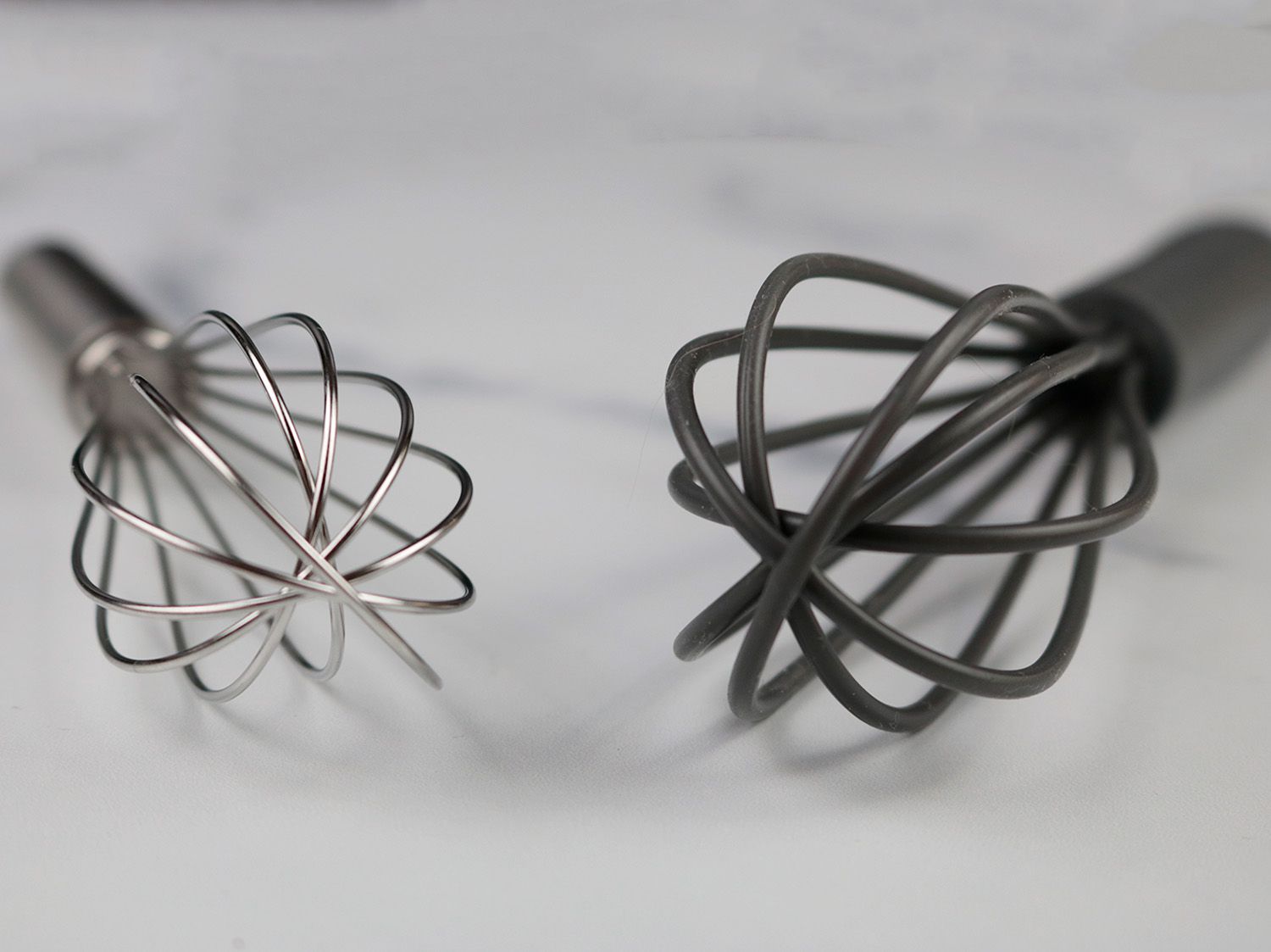 a stainless steel and a silicone coated whisk showing different loop thickness side by side