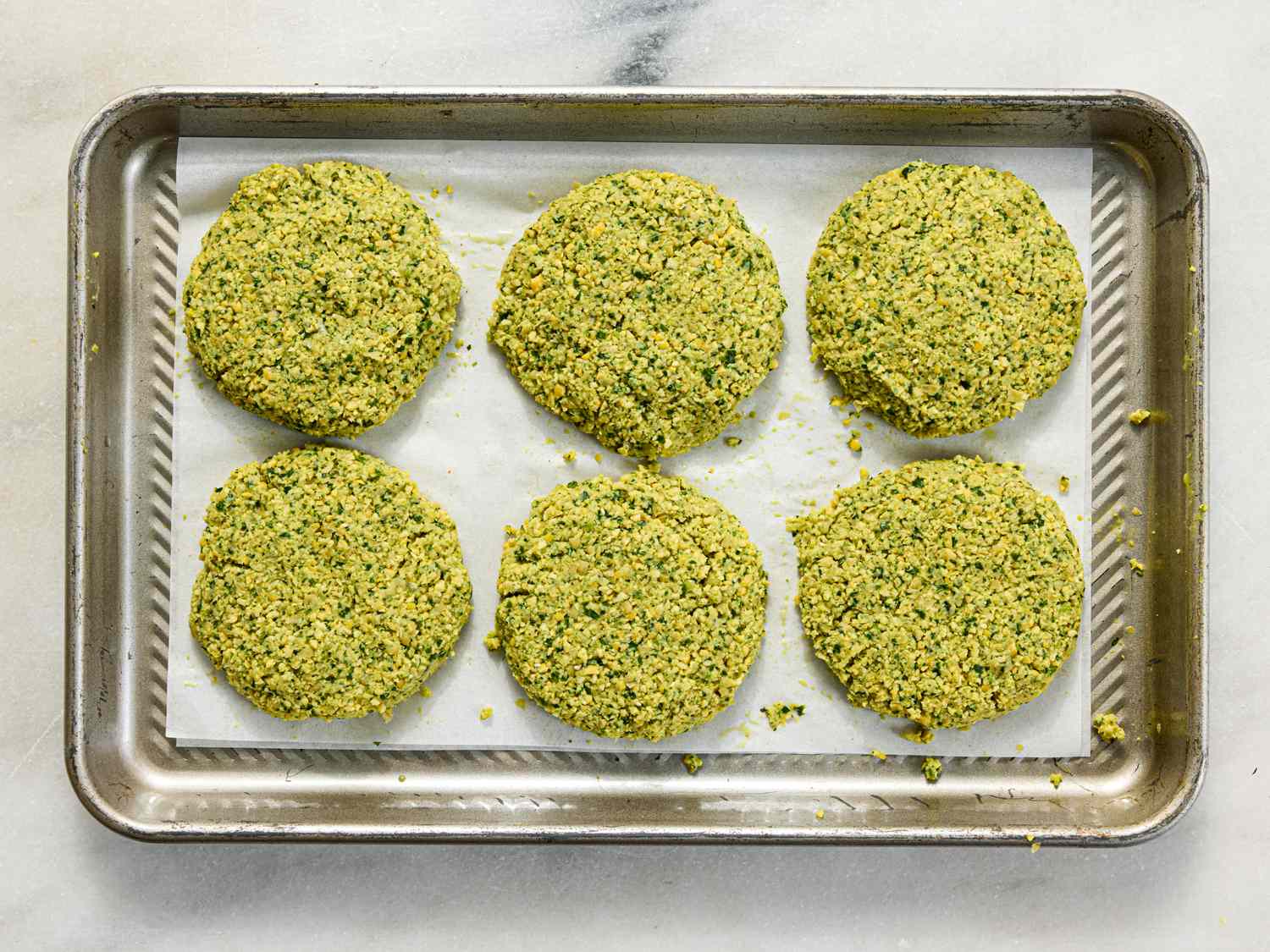 Six falafel patties on a metal baking sheet lined with parchment paper